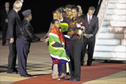 US First Lady Michelle Obama, her daughters Malia Ann, 13, and Sasha, 10, and her mother, Marian Robinson, are greeted by officials as they arrive at Waterkloof Air Force Base in Pretoria.