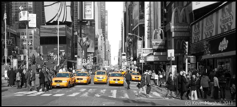 a group of people crossing a street with yellow taxi cabs