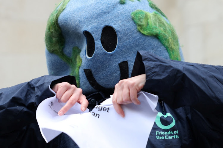 An environmental campaigner tears a piece of paper that says "Carbon budget delivery plan" outside the High Court in London, Britain May 3, 2024.
