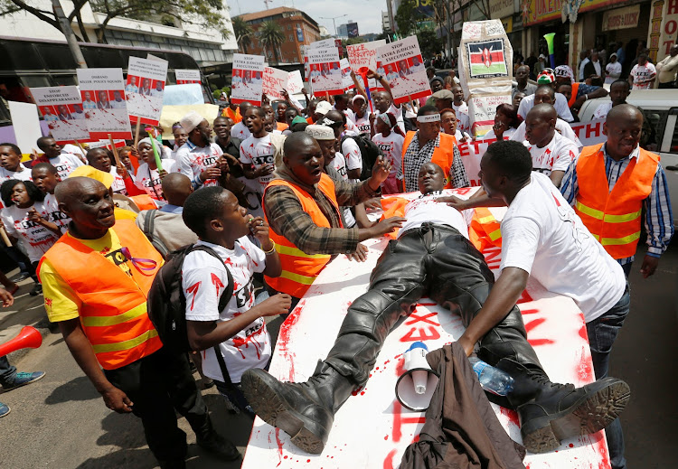 A member of the civil society lies on top of a mock coffin stained with mock blood, as others chant slogans during a protest dubbed "Stop extrajudicial killings" ./FILE