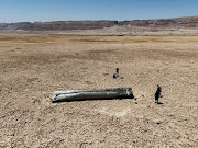 A drone view shows people standing next to the apparent remains of a ballistic missile, in the desert near the Dead Sea, following a massive missile and drone attack by Iran on Israel, in southern Israel April 21, 2024. 