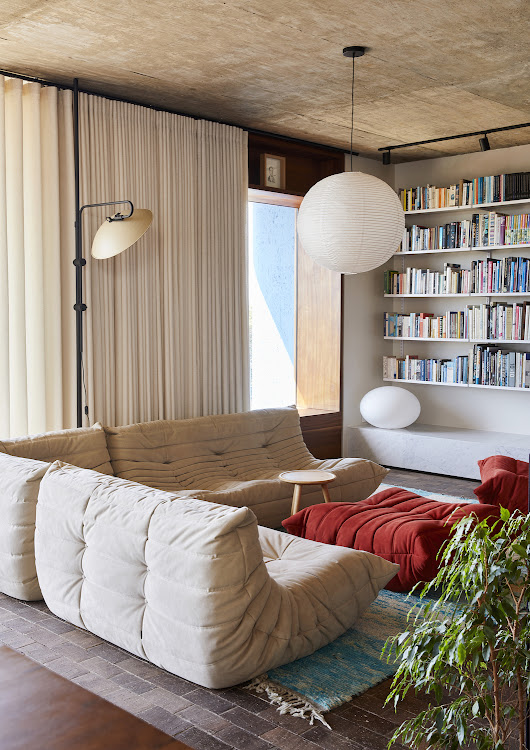 The living area is furnished with mid-century Togo lounge furniture by Ligne Roset, while the Stilt standing lamp is by Joe Paine and the suspended light is by HAY.