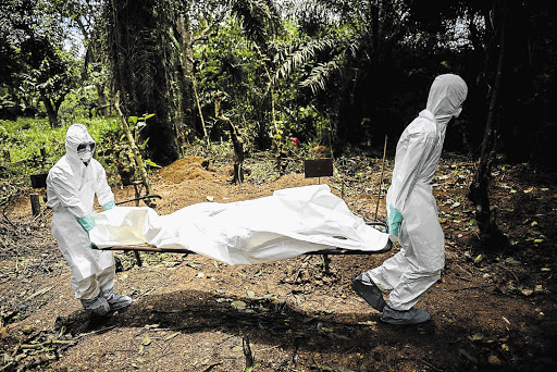 GRIM TASK: Volunteers attend to the burial of Ebola victims in Kenema, Sierra Leone. The Ebola outbreak has killed close to 3 000 people.