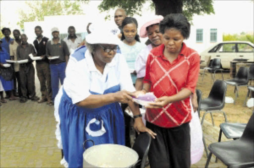 ON A MISSION: Gladys Nkamana of the Mosamaria e Molemo feeding scheme dishes out food to Anna Mpembe. The scheme is run by the Anglican Parish of Saint Philip in Thokoza, Ekurhuleni.Pic: PETER MOGAKI. 19/03/2010. © Sowetan. 20100319PMO:Feeding the hungry:Gladys Nkamana (67) dishes out food to Anna Mpembe (37) one of Thokoza community members on Friday. The Mosamaria E Molema feeding scheme is run by the Anglican Parish of Saint Philip in Thokoza, Ekurhuleni on Mondays and Fridays.PHOTO:PETER MOGAKI