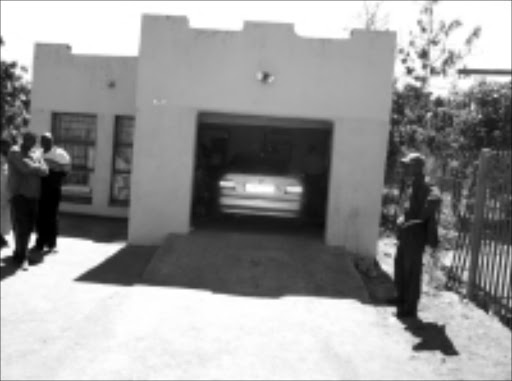 shocked: Family and neighbours in front of the garage in which taxi and bus owner Hassani Amos Mhlanga was shot and killed on Sunday morning. Pic. Victor Hlungwani. 14/09/2008. © Sowetan.