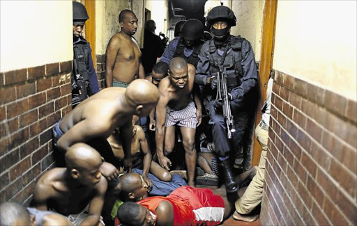 NIGHT RAIDERS: Heavily armed police, supported by troops in armoured vehicles, raided the Wolhuter men's hostel in Jeppestown, Johannesburg, last night, searching rooms and occupants for weapons. The area has been wracked by xenophobic violence in recent days Image by: ALON SKUY