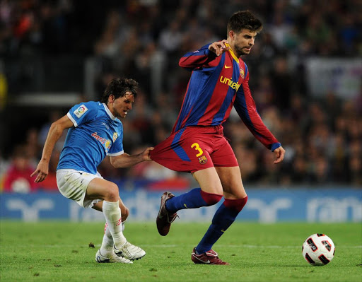 Pablo Piatti (L) of Almeria tries to stop Gerard Pique of Barcelona by holding on to his shorts during the La Liga match at the Camp Nou stadium on April 9, 2011 in Barcelona, Spain