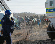 Striking miners armed with weapons in Marikana, North West, were fired upon by police brandishing assault rifles in August 2012. File photo.