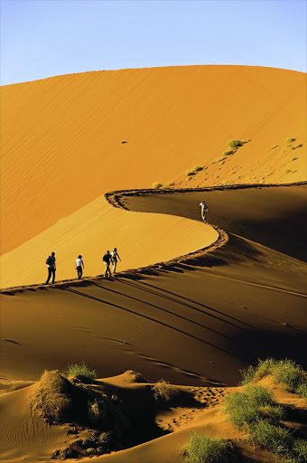 Tourists climb a dune near Sossusvlei in the Namib Naukluft National Park.