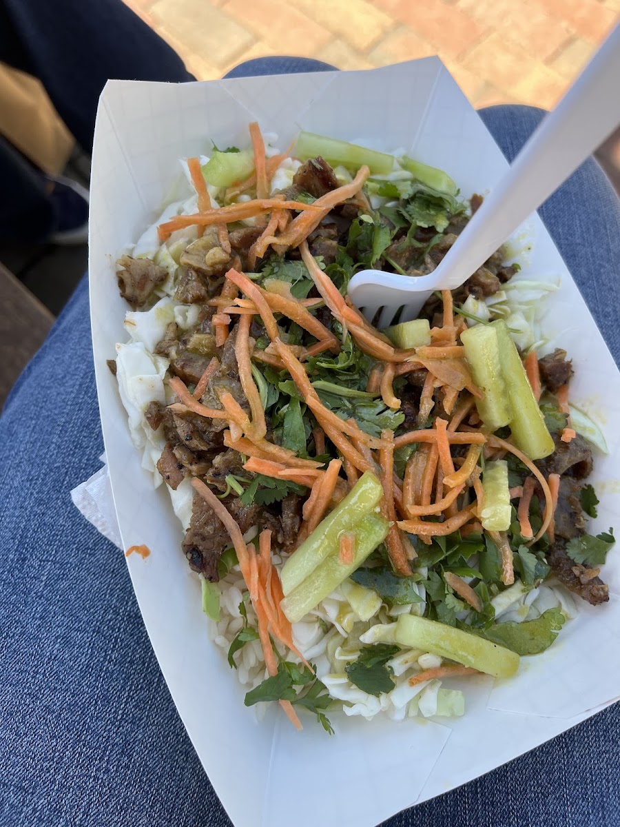 Cabbage and rice bowl with lemongrass pork, pickled carrots, cucumber, cilantro, and a cilantro-lime dressing