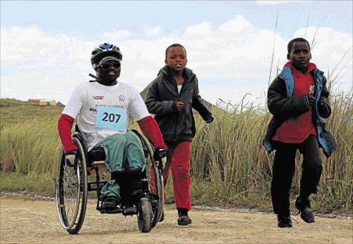 OFF HE GOES: DECEMBER 3, 2015 ON A ROLL: A participant in one of last year’s Rolling Hills wheelchair races at Madwaleni Hospital near Elliotdale is supported by two young friends. The races will be held for the seventh time on Sunday