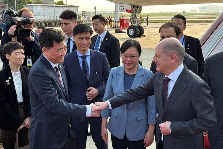 German Chancellor Olaf Scholz shakes hands with Chinese ambassador to Germany Wu Ken next to Chongqing Vice Mayor Zhang Guozhi, upon arriving at the airport in Chongqing, China, April, 14 2024. Picture: REUTERS/Andreas Rinke