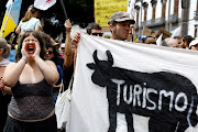 A woman shouts next to a banner painted with the word 'Tourism' during a demonstration in Santa Cruz de Tenerife, Spain, on April 20 2024.