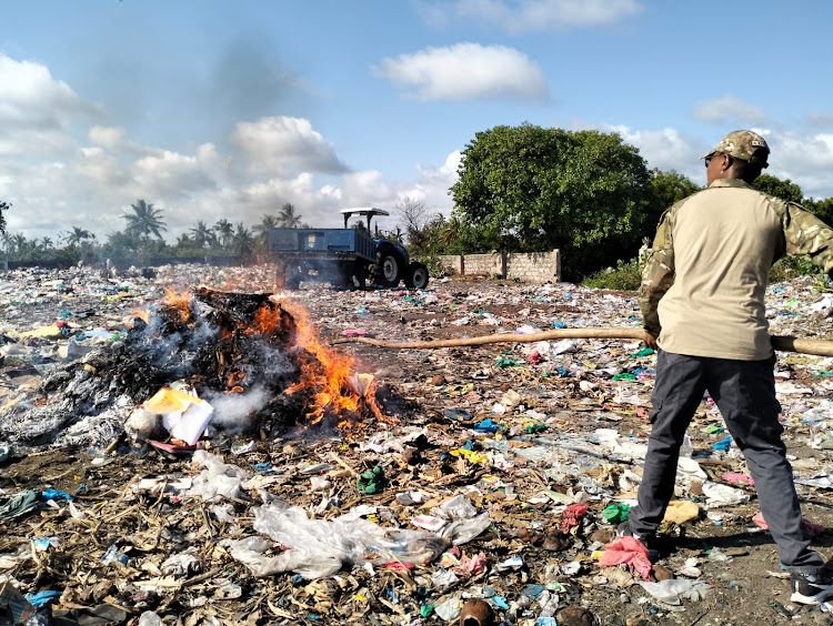 A police officer trying to ensure all the narcotics and old court record are completely destroyed through burning at the Kashmir Dumpsite on Lamu Island.