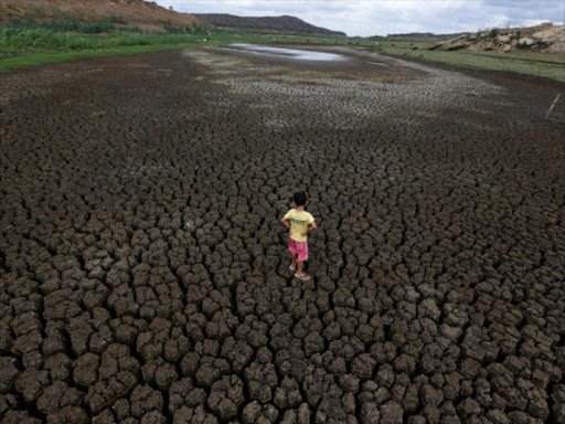 A boy stands on the cracked ground of the Boqueirao reservoir in the Metropolitan Region of Campina Grande, Paraiba state, Brazil, February 13, 2017. /REUTERS