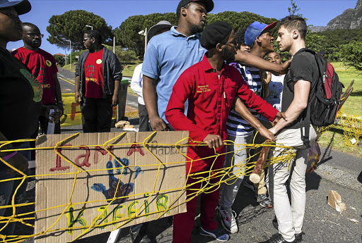 Black students at the University of Cape Town confront a white colleague during recent protests on the campus; the author says anti-white sentiment is mushrooming at universities, rooted in the writings of Frantz Fanon.