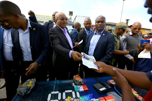 A vendor lights a cigarette, seemingly unmoved by the hubbub created by President Jacob Zuma's visit to Marabastad near Pretoria. The president wanted to find out what he should say on Thursday in his state of the nation address in Cape Town.