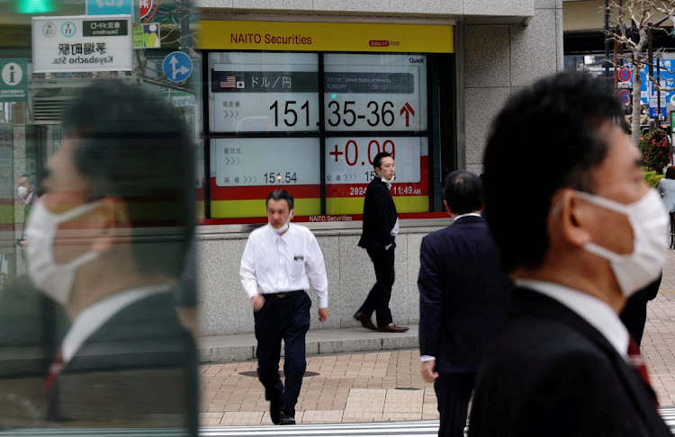 Pedestrians walk past an electric monitor displaying the Japanese yen exchange rate against the US dollar outside a brokerage in Tokyo. File photo: KIM KYUNG-HOON/REUTERS
