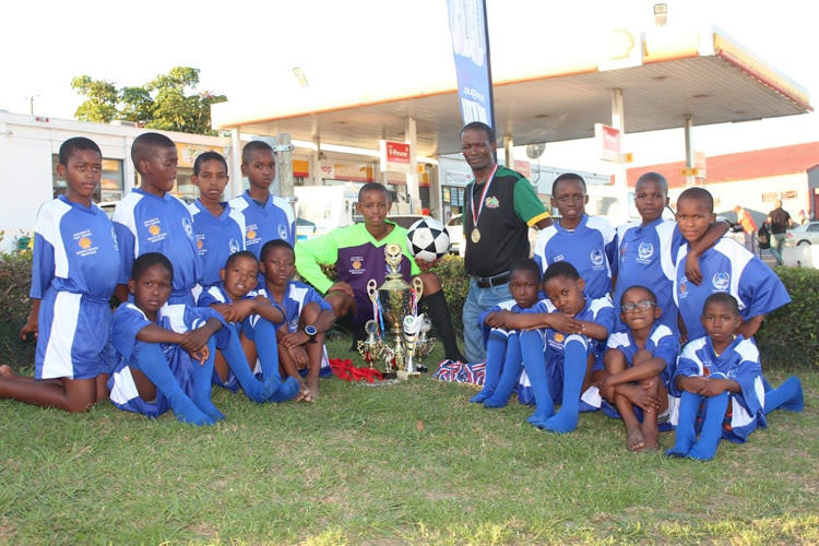 Mdantsane resident Nzimeni Fanta and his soccer club, Blue Aces, show off a trophy the U13 team won during an Easter tournament