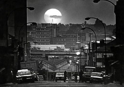 June 8, 1976. The setting sun casts a golden glow over the buildings, aerials and motorways of Johannesburg. A Golden city in its 90th anniversary year.