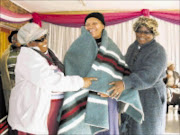 CUDDLY: Lucy Thusi, left, and Sarah Magoro, right, both of Simunye Mbokodo, wrap a blanket around 70-year-old Catherine Zulu . Pic: Penwell Dlamini. 27/06/2009. © Sowetan.