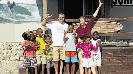 THE SKY IS THE LIMIT: Pro surfer Bianca Buitendag, right, cuddles champion surfer Zia Hendricks while her brother, Dillon, and mentor Thys Strydom and the rest of the Pelrus groms who will be going to school with her look on Picture: SUPPLIED
