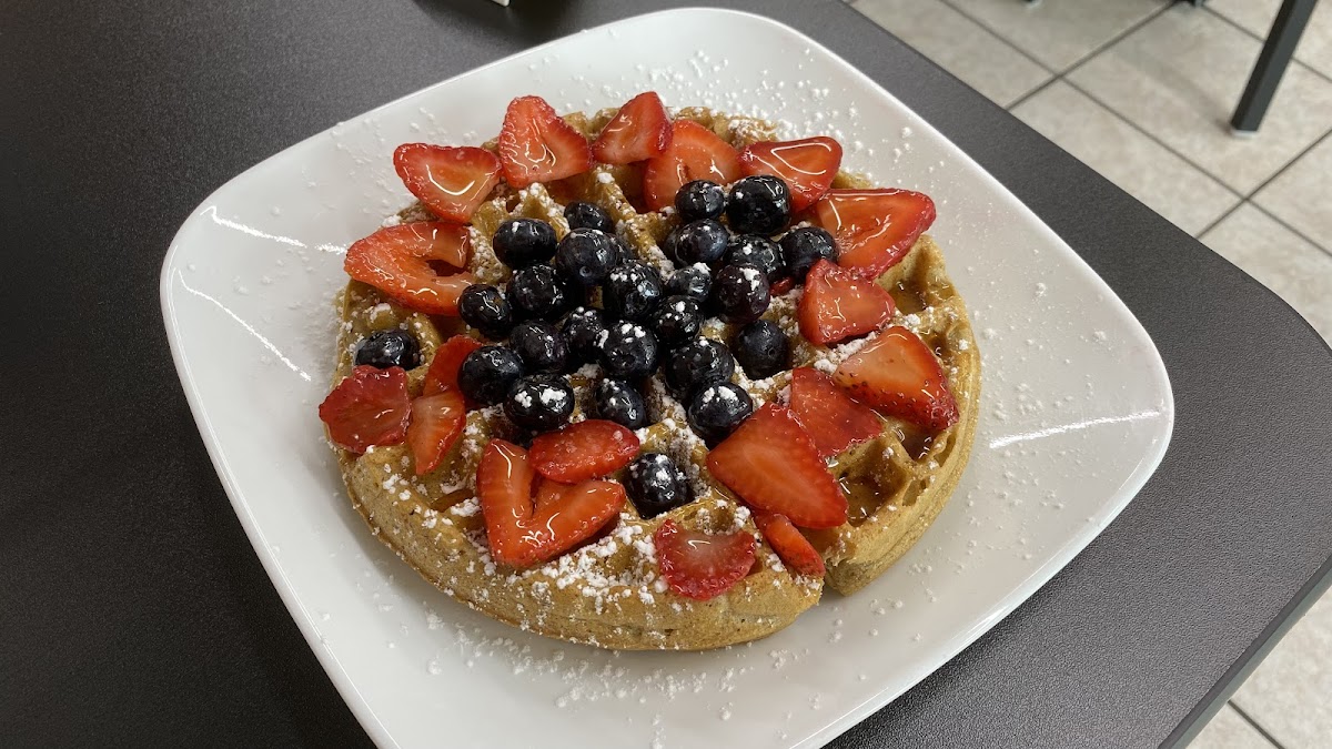 "Gluten friendly" waffle with blueberries, strawberries, powdered sugar, and syrup.