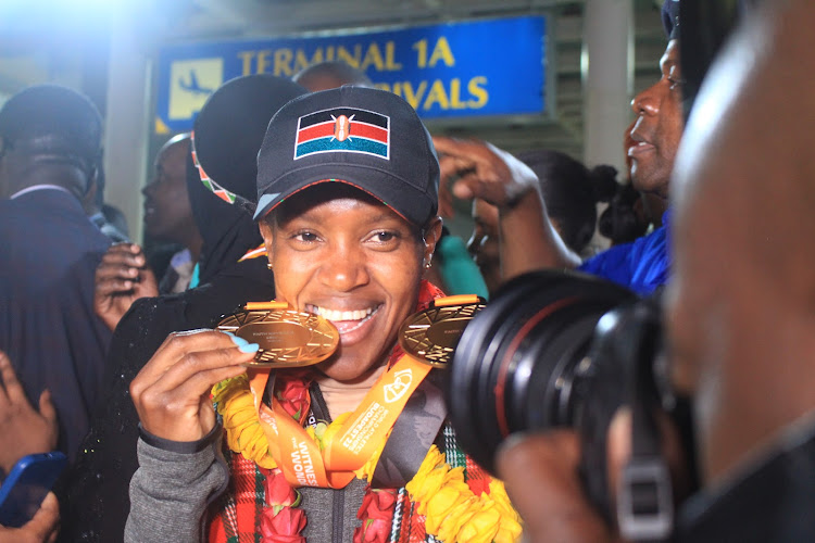 Triple world record holder Faith Kipyegon displays her gold medals upon arrival at the JKIA from the 2023 Budapest World Athletics Championships