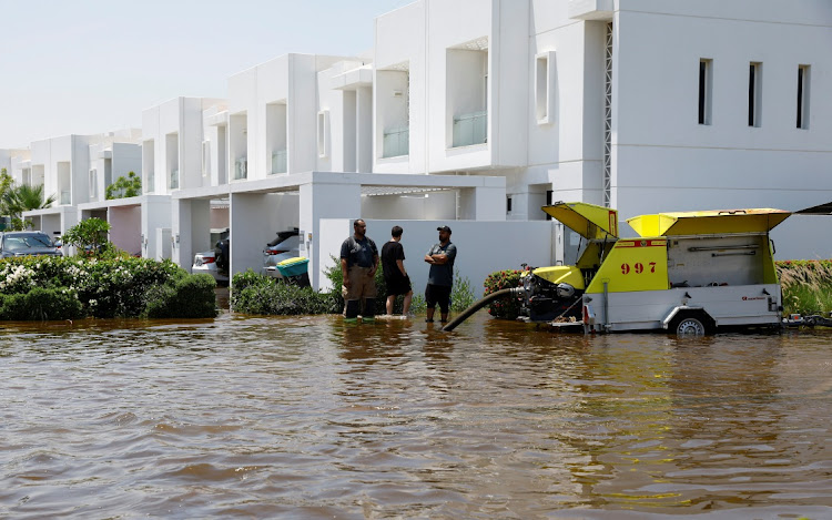 Members of a fire and rescue team stand next to a truck pumping out water that has gathered due to heavy rains, in a residential community in Dubai, United Arab Emirates. Picture: Reuters/Rula Rouhana
