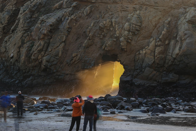 A sun ray passes through Keyhole Arch near the Pacific Coast Highway.