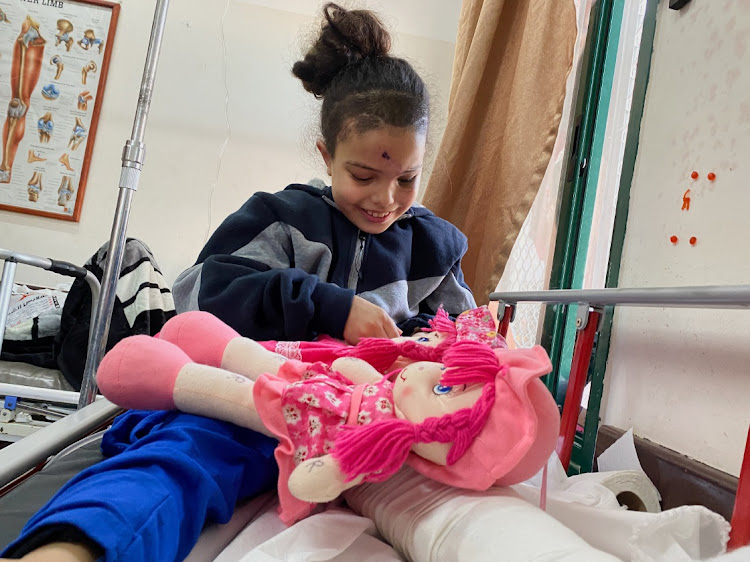 Razan Shabat, a displaced orphaned Palestinian girl who was wounded in an Israeli strike and whose parents were killed in a strike on a house they were sheltering in, plays with dolls at a hospital, amid the ongoing conflict between Israel and the Palestinian Islamist group Hamas, in Deir Al-Balah on December 11, 2023. Picture: REUTERS/Doaa Rouqa