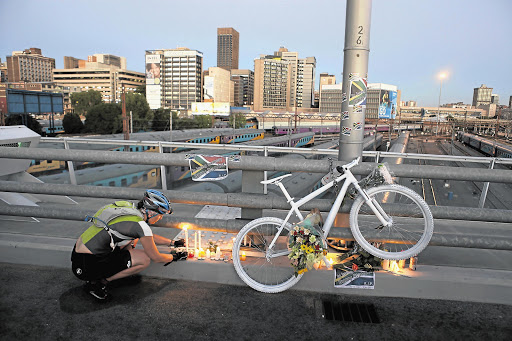 A cyclist lights a candle under a 'ghost bike' that was chained to the Nelson Mandela Bridge in Johannesburg on Friday night as a tribute to Olympic cyclist Burry Stander, who was killed this week