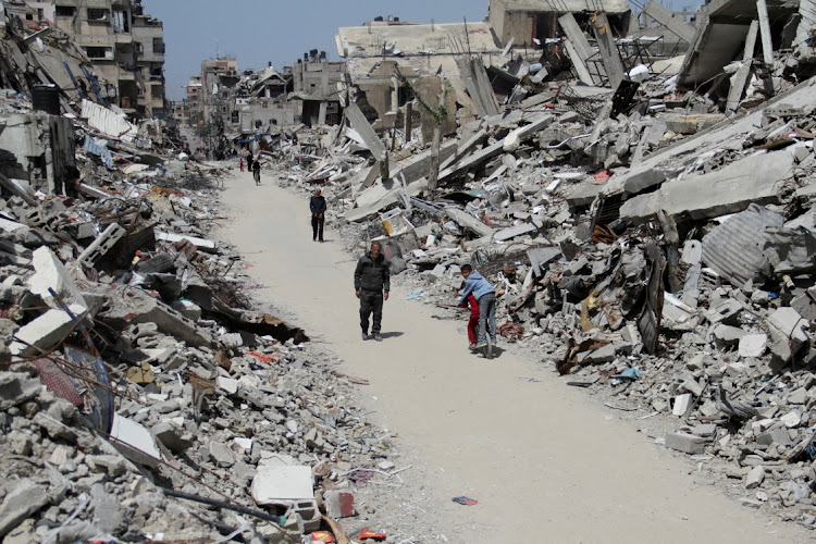 Palestinians walk past the ruins of houses and buildings destroyed during Israel’s military offensive.