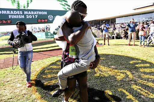 Comrades Marathon winner Bongmusa Mthembu embraces his son Sisanda after winning his second title yesterday. Women's winner Camille Herron, from Oklahoma, US, almost missed out. She stopped running when she entered the arena, got a rose and thought it was the finish line See Page 20 Picture: JACKIE CLAUSEN