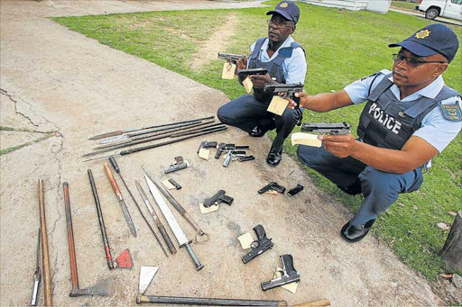 PREPARED: Bhityi police's Warrant Officers Mzuvelile Maqanda and Sivuyile Sapho display some of the weapons seized near Bhityi