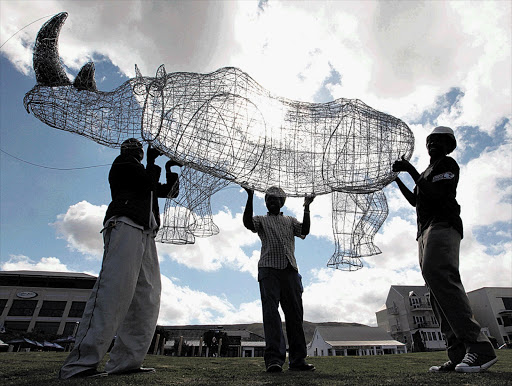 Hermanus-based sculptor Farayi Mukonde, left, helped by Blessing Jeremani and Bongani Chenera, with his 80kg rhino. The artwork will be auctioned in Joburg at the end of the month and the funds will go to Clive Walker's Living Museum and Rhino Care Centre, which helps rehabilitate ill, injured or orphaned rhinos Picture: ESA ALEXANDER