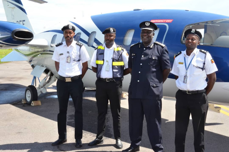 Police spokesperson Fred Enanga poses with officers of the Police Air wing department at Entebbe International Airport