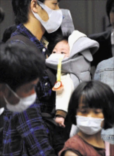 Travelers arriving from overseas with their children wait in a long line all wearing masks to go through quarantine at Narita International Airport in Narita, east of Tokyo, Tuesday, May 5, 2009, Children's Day national holiday. Japanese holiday makers' return to their home country has come to its peak Tuesday as the "Golden Week" holidays ends on Wednesday, May 6 amid the global swine flu fears. (AP Photo/Katsumi Kasahara)