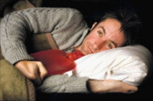 CUDDLED UP AND COSY: Shaun Brain Murphy gets hot under the covers testing hot water bottles for our cold winter nights. 13/05/2009. Pic. Daniel Born. © The Times.