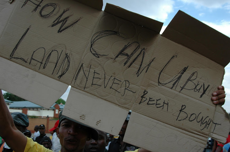 How Can U buy land Never Been Bought, placard held by an ANCYL supporter.