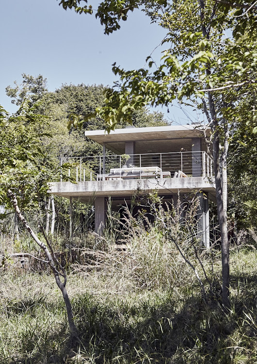 When approached from below, the house is nestled in its surroundings, with vegetation growing right up to it.