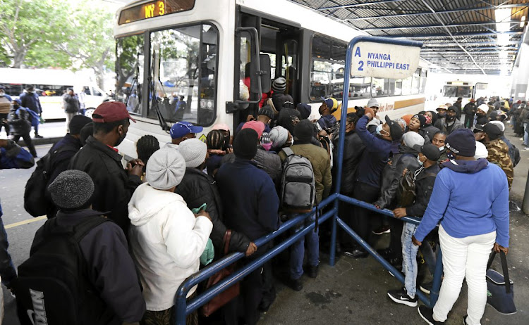 Commuters queue to board a bus during the ongoing taxi war in the Western Cape. File photo.
