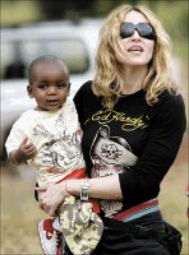 MATERIAL MOM: Madonna arrives in Britain with baby David Banda whom she hopes to adopt. Pic. Karel Prinsloo. 17/04/07. © AP.