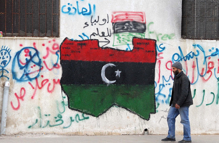 A man walks past graffiti of the flag that has been adopted by the rebel movement in eastern Libya on 16 March 2011.