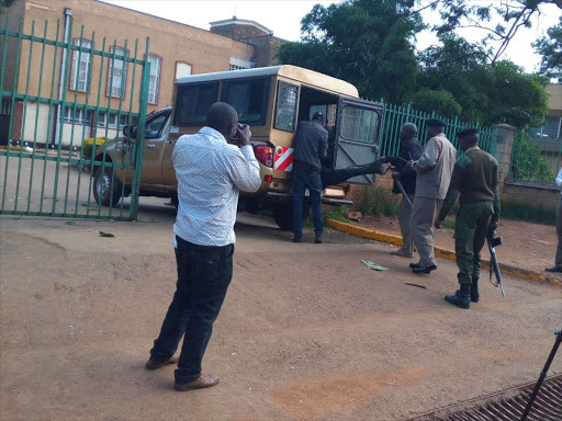 Security officers remove the body of street boy that had been dumped at the entrance to the county offices in Eldoret