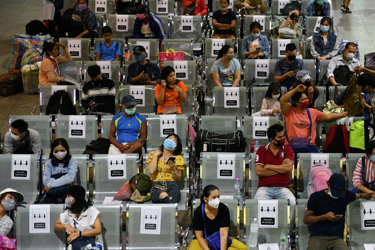 People wearing protective face masks sit on social distancing benches at a bus station after many activities have been closed due to the coronavirus outbreak in Thailand on March 22 2020.