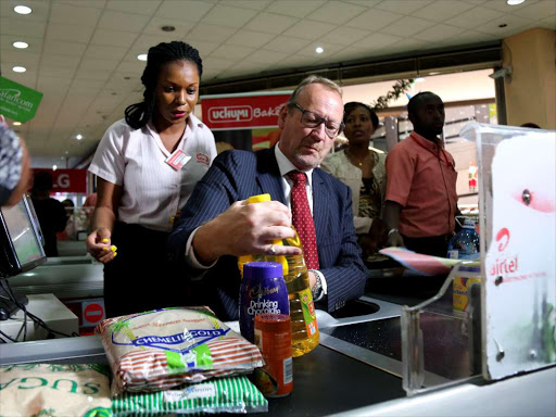 Uchumi Supermarket chief operation officer Andrew Dixon is helped by an attendant to serve customers after Uchumi holdings restocked all its branches countrywide on December 21,2017.Photo/Enos Teche.