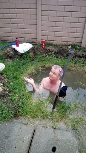 Democratic Alliance councillor Tim Denny bathes in a sinkhole a burst pipe created in his backyard in Secunda, Mpumalanga.