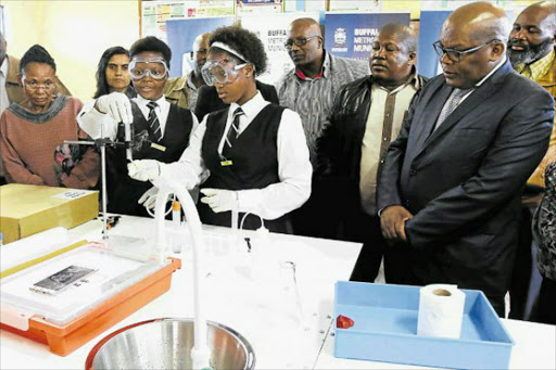 INQUISITIVE YOUNG MINDS: Pupils from Sandisiwe SSS in Mdantsane NU14 making use of the newly donated mobile lab. Anda Mkhonjwa and Lisakhanya Nazo do the honours with the inaugural experiment as Mayor Xola Pakati looks on Picture: MICHAEL PINYANA