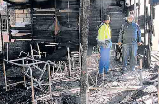 JULY 19, 2016.Standing on the ashes of Qonce High School classrooms which were burnt in a fire in the early hours of yesterday morning are school principal Xhasumzi Mrwashu and the caretaker.Picture: SILUSAPHO NYANDA © DAILY DISPATCH